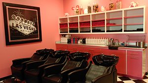 four hair washing stations in a pink room with a Las Vegas Sign picture on the wall