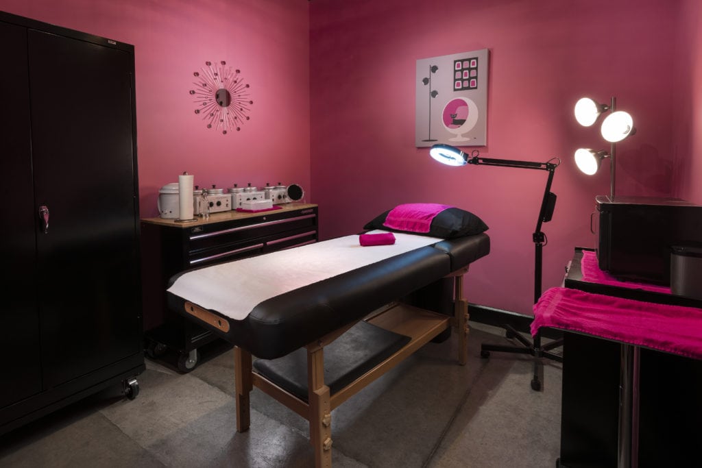 Pink room with waxing table, wax materials and lights in the right corner